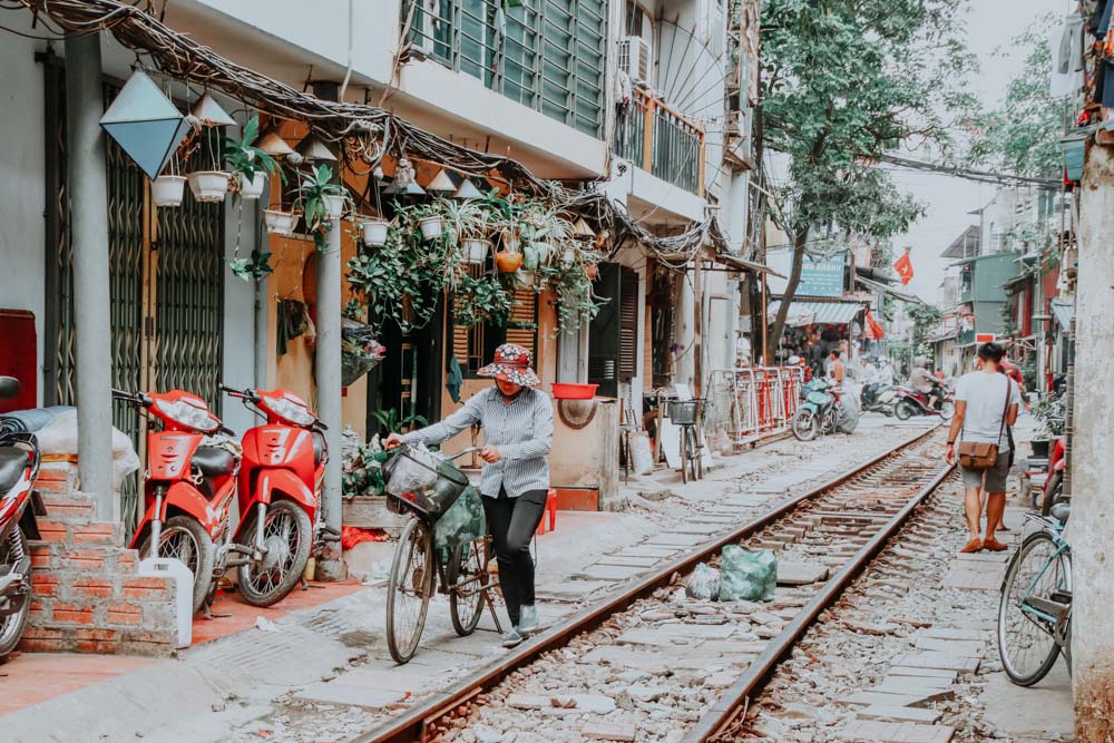 Frau schiebt ihr Fahrrad durch die Hanoi Train Street